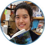 Jessica behind the counter reading a copy of The Reader by Traci Chee